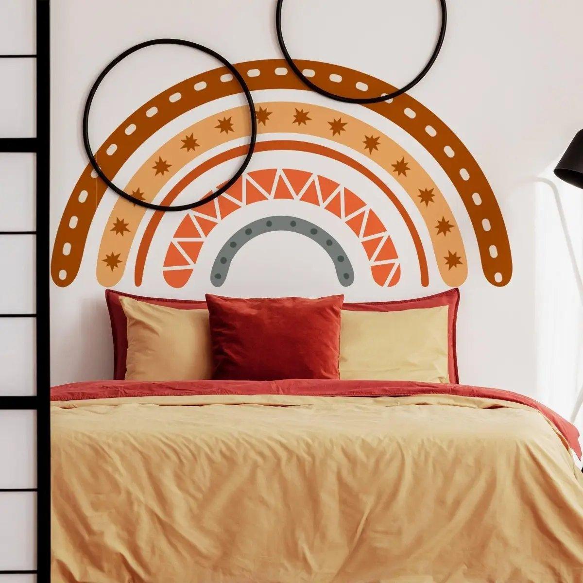 Boho chic multicolor rainbow wall art above a cozy bed with red and beige pillows.