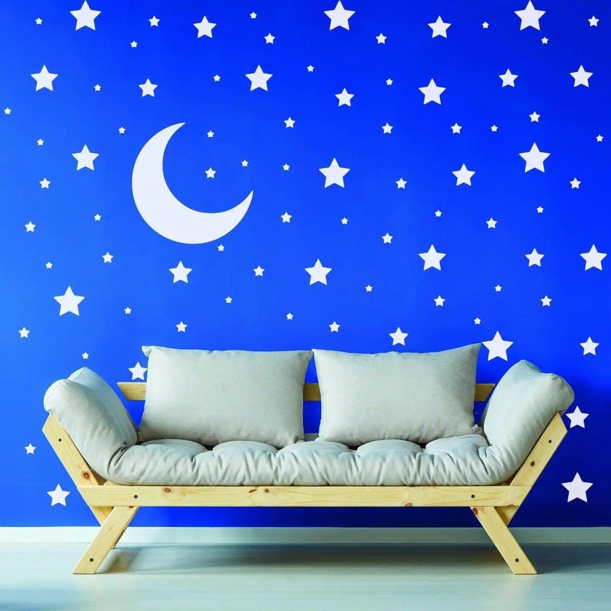 Celestial Dreams wall decals featuring white stars and a crescent moon on a blue wall above a cozy sofa.