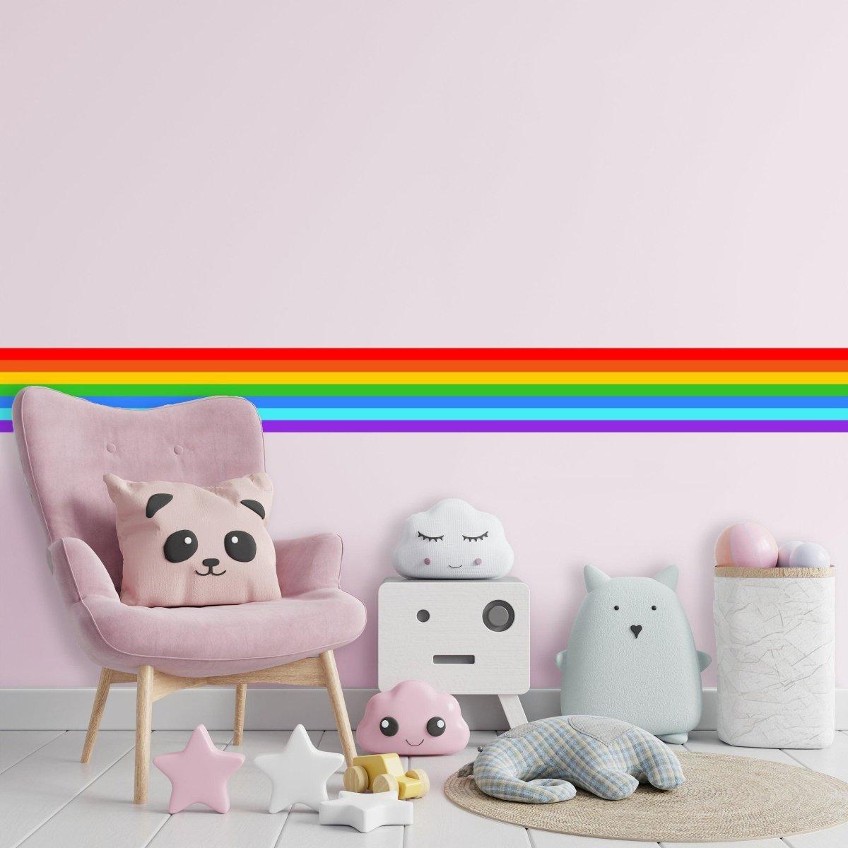 Vibrant rainbow stripe wall decal above a cozy children's corner with plush toys and a pink chair.
