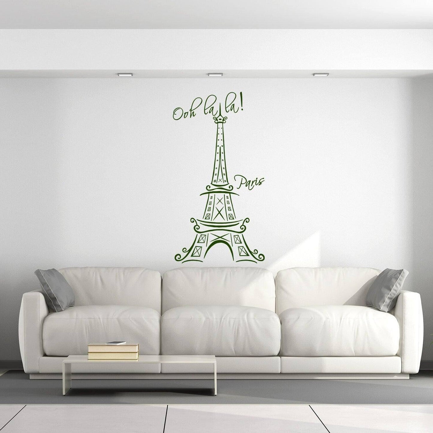 Eiffel Tower vinyl decal with 'Ooh la la!' text on a white wall above a modern couch in a stylish interior.
