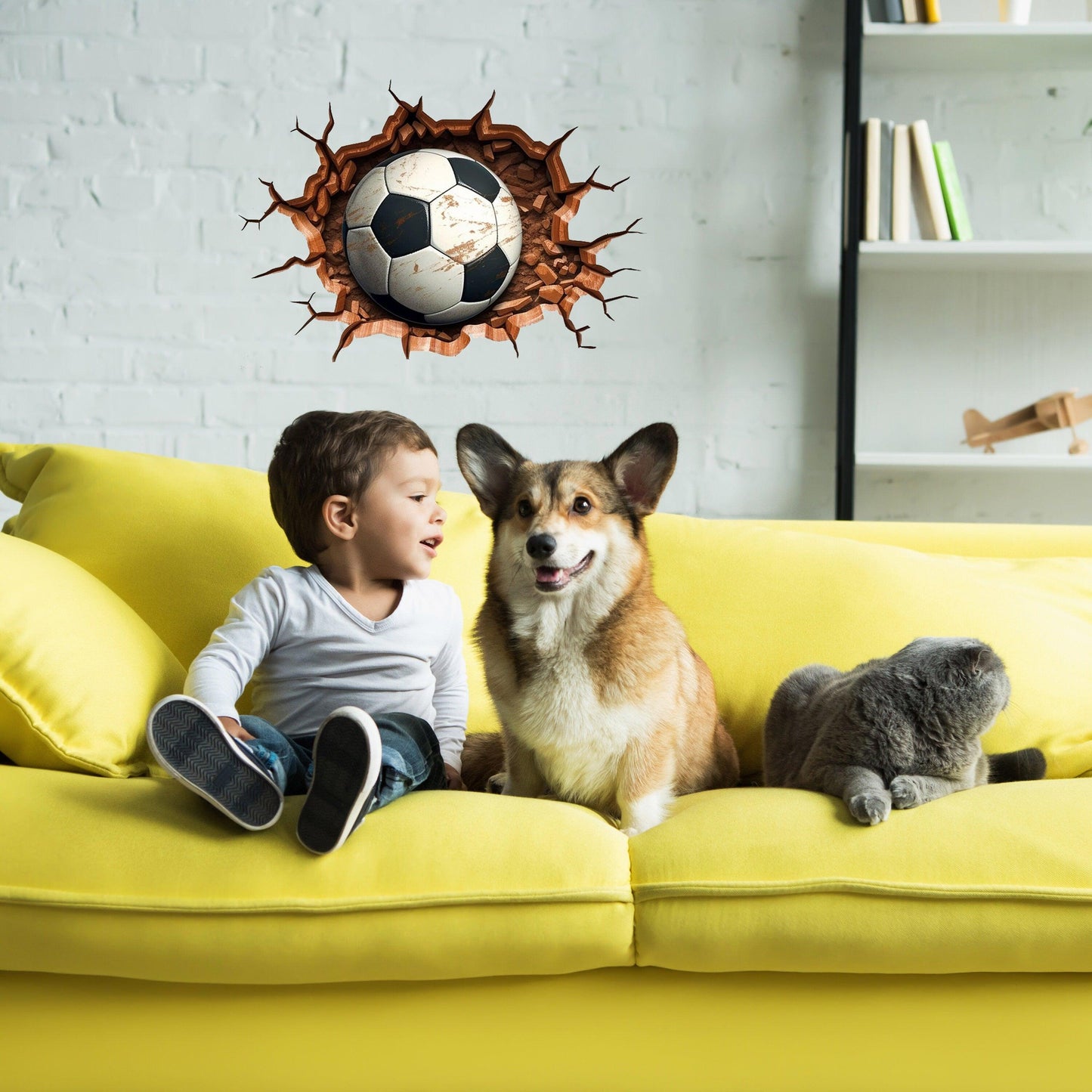 Boy and dog on yellow couch with 3D football wall decal for sporty kids room decoration.