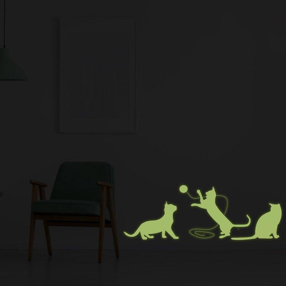 Glow-in-the-dark feline wall decal featuring playful cats in silhouette against a dark room backdrop.