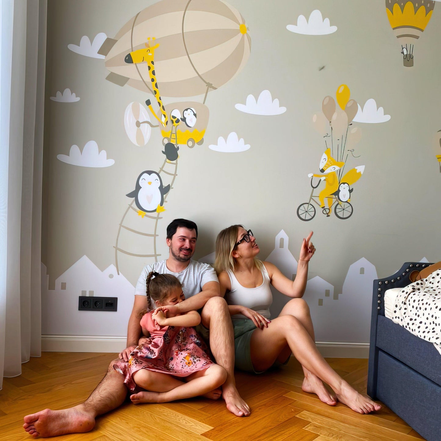 Family enjoying a playful nursery with WhimsyLand wall decals featuring penguins, foxes, and hot air balloons.