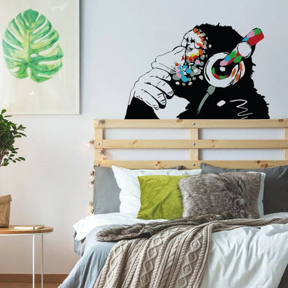 Banksy-inspired thinking monkey wall sticker with headphones in a stylish bedroom decor.