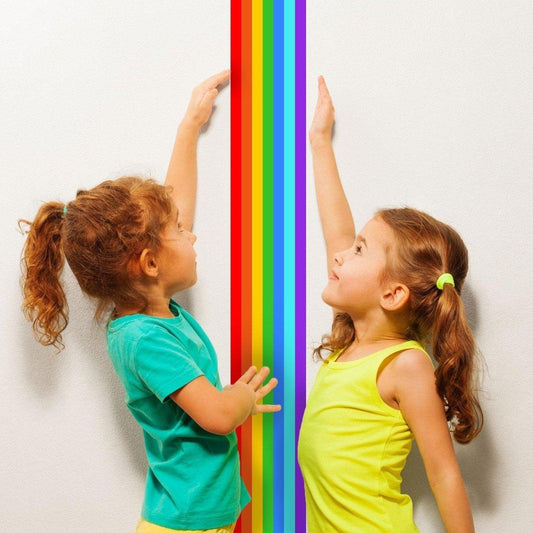Two children reaching for a vibrant rainbow stripe wall decal, showcasing bright colors and playful energy.