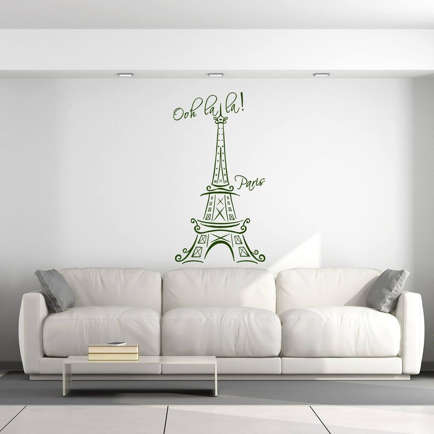 Eiffel Tower vinyl decal with 'Ooh la la!' text on a white wall above a modern couch in a stylish interior.