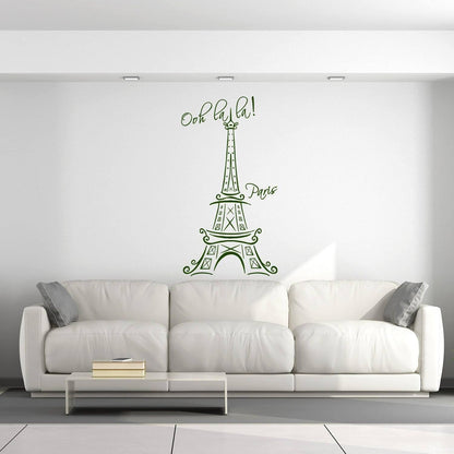 Eiffel Tower vinyl decal with 'Ooh la la!' text on a white wall above a modern couch in a stylish interior.
