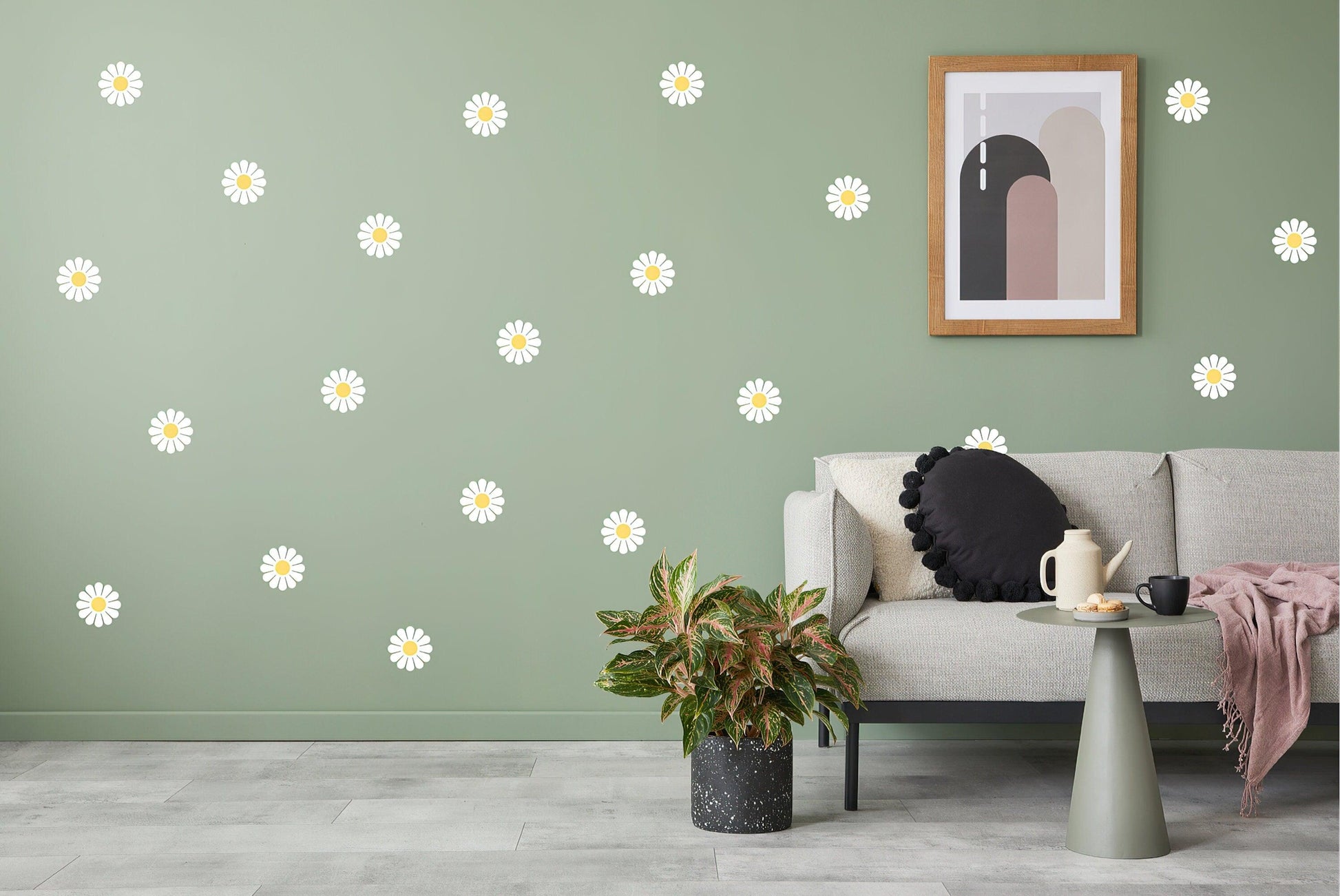 Elegant white daisy wall decals on a green wall, styled with a cozy living room setting and modern decor.